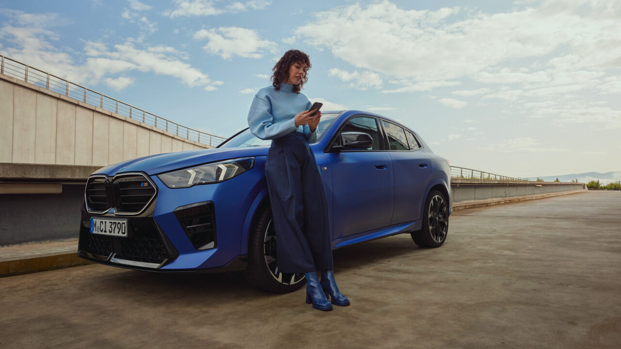 Vrouw leunt tegen haar blauwe BMW